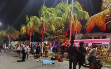Peritos y autoridades realizan diligencias en la avenida principal de Celestún tras un accidente de motocicleta. Evitar mostrar los cuerpos de las víctimas.